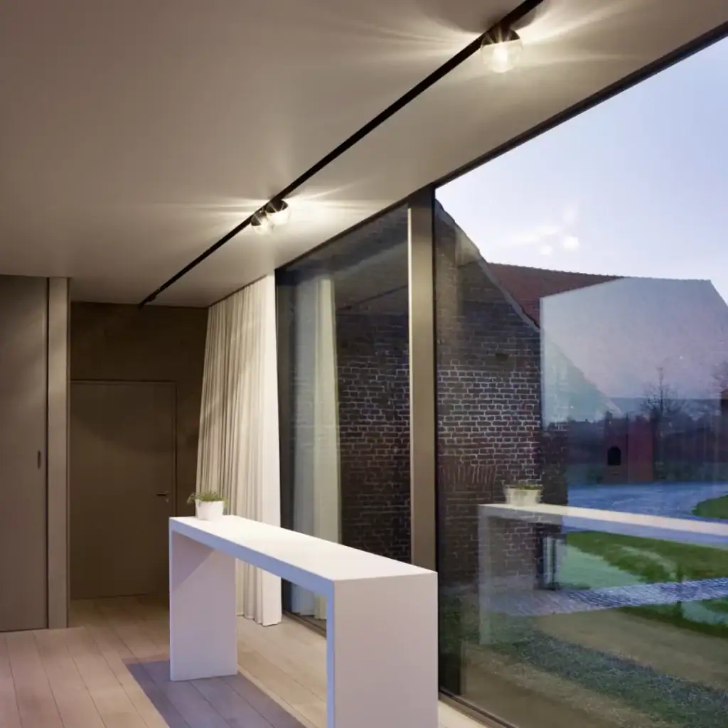 Delta Light Splitline track light along a ceiling with floor-to-ceiling windows at dusk