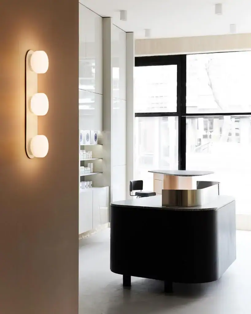 RBW Pastille wall light, three lit globes in a vertical row near a reception desk