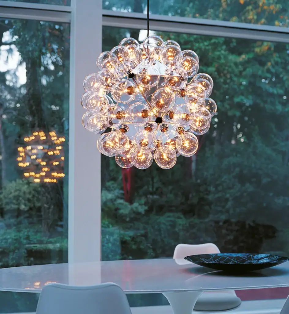 Flos Taraxacum 88 pendant lit above an outdoor dining table at dusk