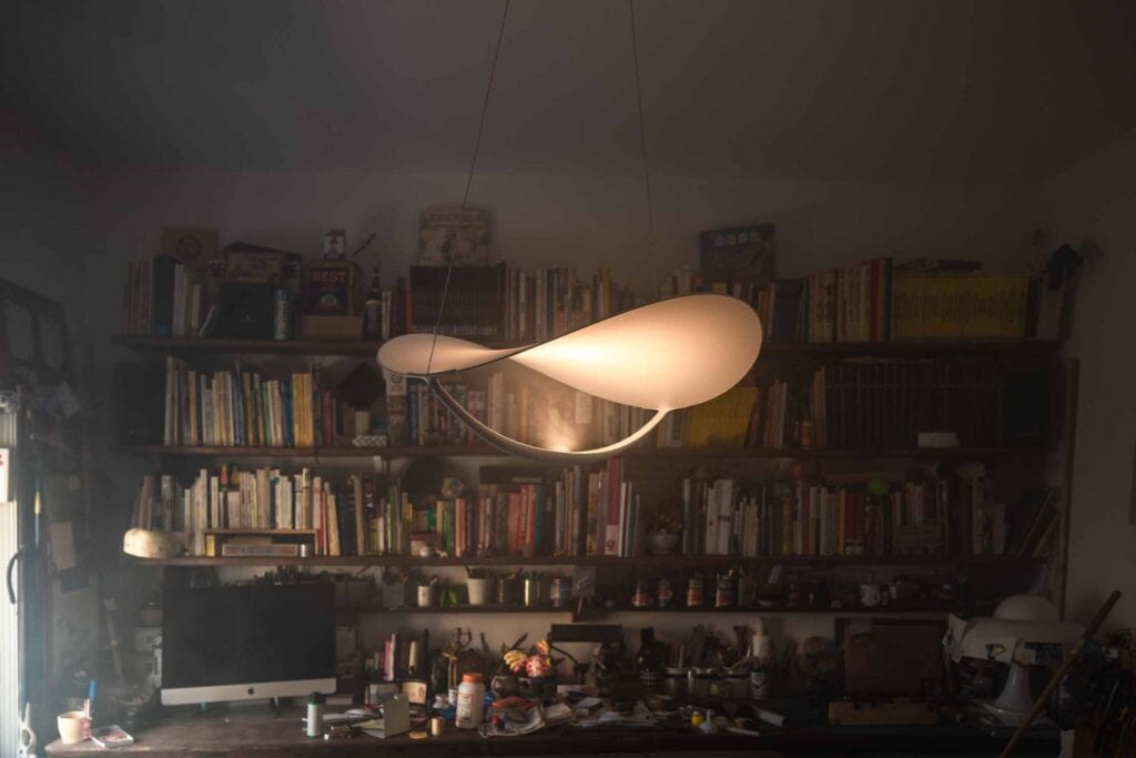 Foscarini Plena pendant lit above a bookshelf in a study