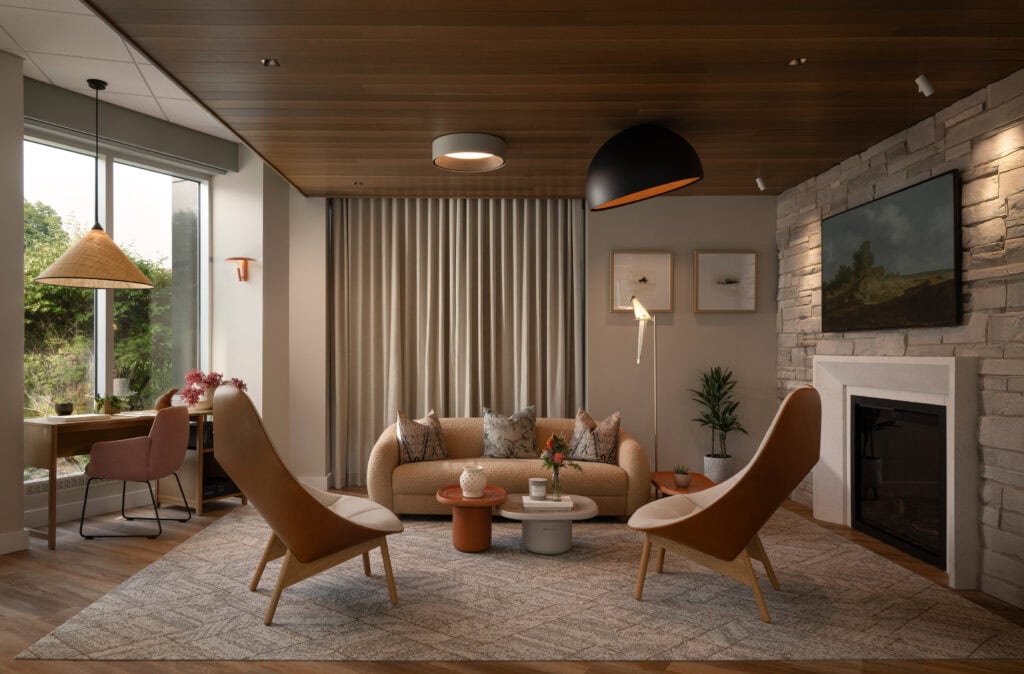 The living room vignette at the Flux showroom in Ottawa: a stacked-stone fireplace wall lit from above so the courses read in relief, with a smooth painted wall and framed art beside it.