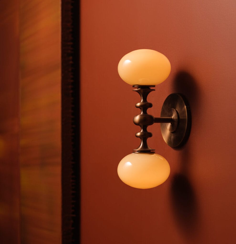 Decorative wall sconce with two frosted glass globes and black metal accents.