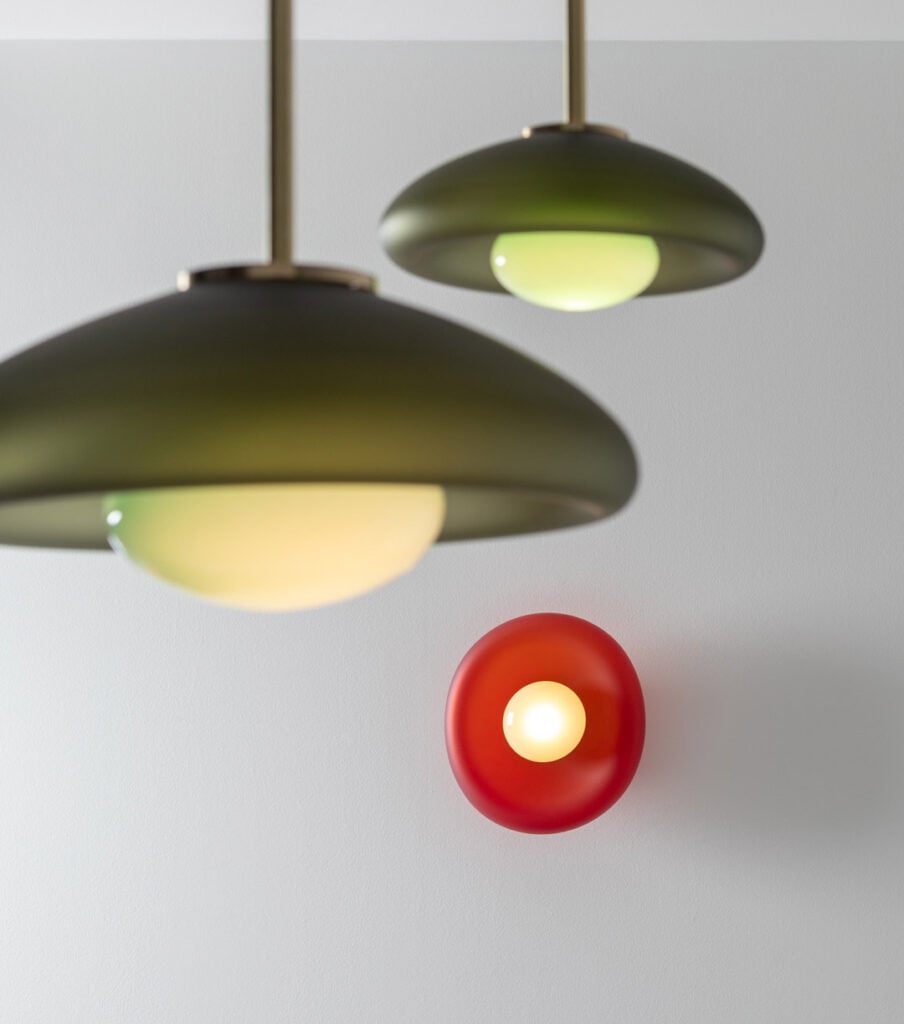 Modern pendant lights with green and black shades and a red wall sconce.