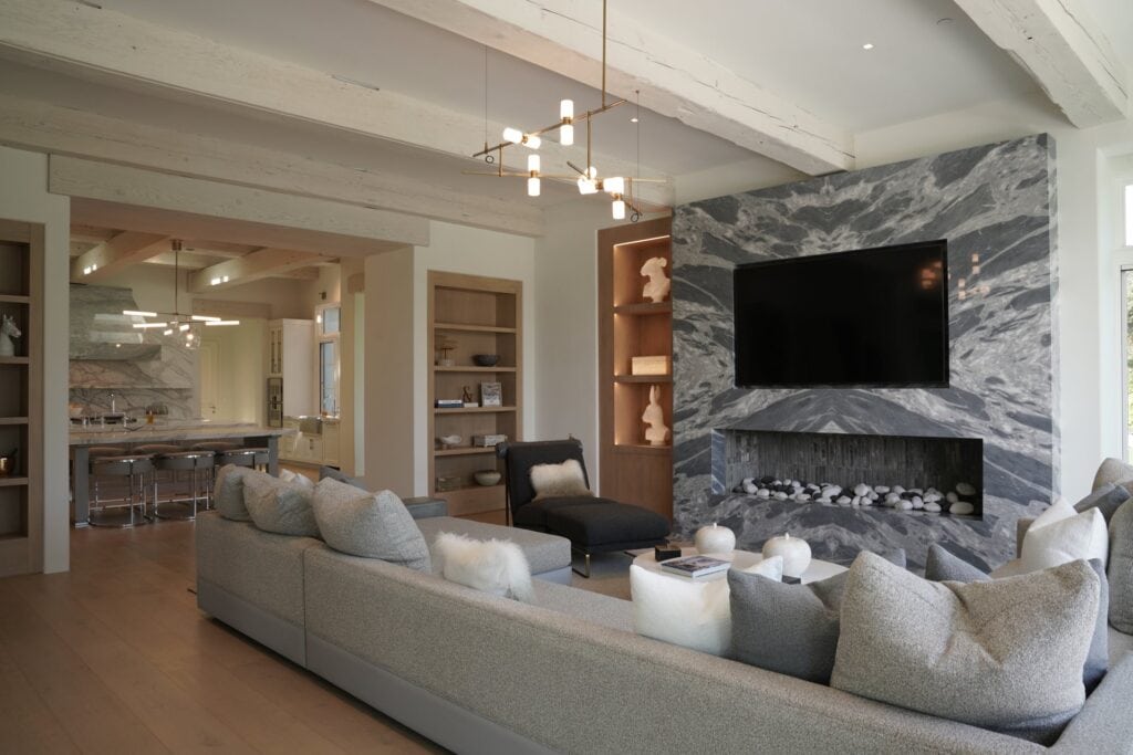 Modern living room with a marble fireplace wall and Sonance in-wall speakers hidden from view