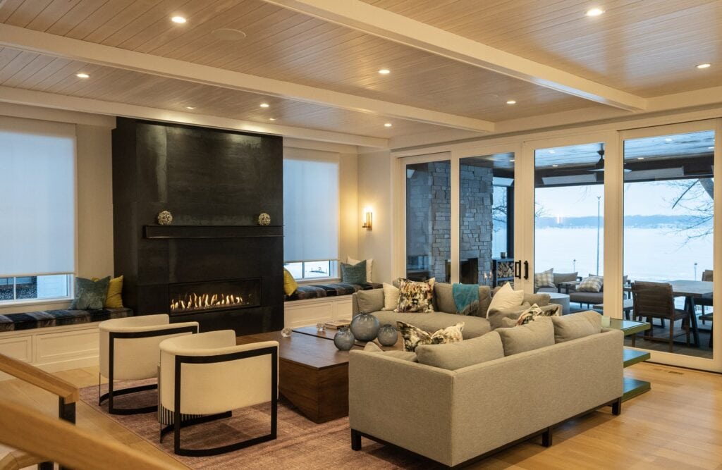Lakehouse living room with a wood-beam ceiling and Sonance invisible speakers