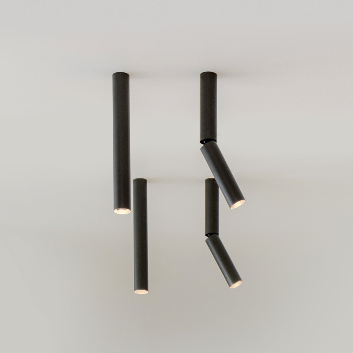Four black Delta Light Needle tube spotlights, two hanging straight and two angled