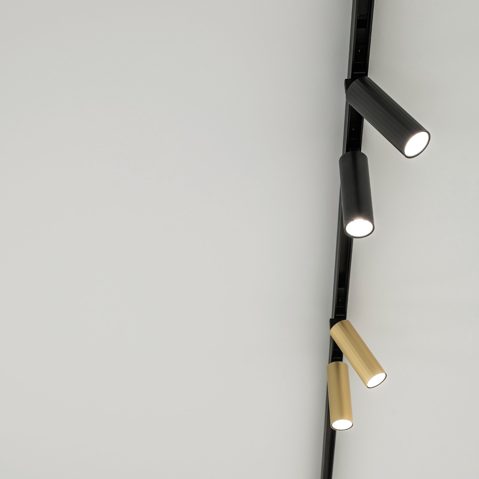 Delta Light Shiftline track on a white ceiling with black and brass spotlights